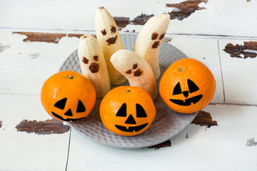 Painted funny faces on tangerines and bananas for Halloween
