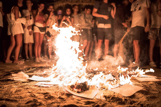 Hoguera de San Juan en la playa con llamas, fuego y personas