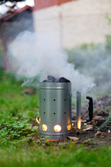 Fototapeta na wymiar Firing up charcoal before barbecue in Charcoal Chimney Starter