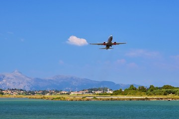 Fototapeta na wymiar Start of an aircraft at the airport of Corfu - Greece. A short and dangerous airport in the sea with the mountains in the background.
