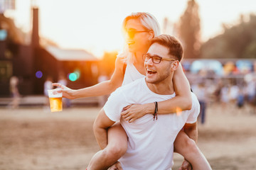 Young couple piggy backing at music festival