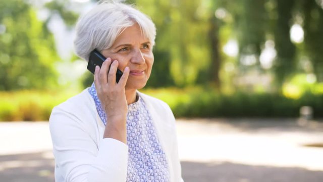 retirement, communication and old people concept - happy senior woman calling on smartphone in summer park