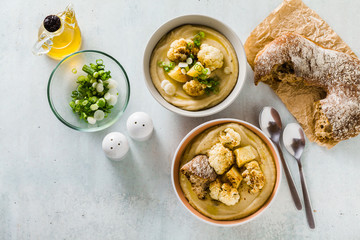 cream soup of cauliflower and potatoes in bowls on a table with fresh bread and green onions. healthy vegan cuisine.