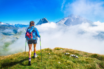 A girl during a hike in the mountains with poles sticks