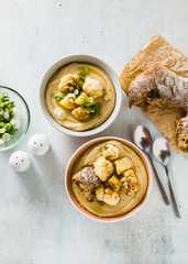 cream soup of cauliflower and potatoes in bowls on a table with fresh bread and green onions. healthy vegan cuisine.