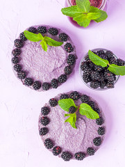 Raw blackberry dessert decorated with fresh ripe forest berries and green mint leaves and blended...