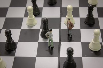 Top view miniature businessman negotiate for cooperation on chess board with chess.