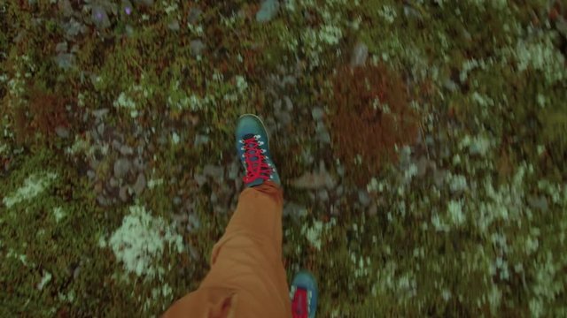 Man in khaki brown pants and bright blue hiking boots with red laces walks on different terrain, stones, rocks, moss, grass, volcanic soil. concept adventure and exploration gear for active lifestyle
