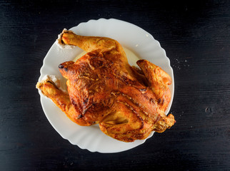 fried chicken whole, on a white plate on a wooden background