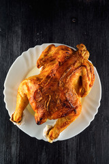 fried chicken whole, on a white plate on a wooden background