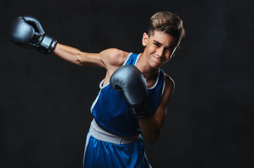 Fototapeta na wymiar Handsome young boxer during boxing exercises, focused on process with serious concentrated facial. Isolated on a dark background.