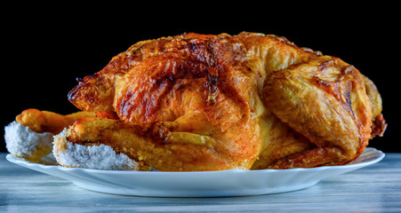 fried chicken whole, on a white plate on a wooden background