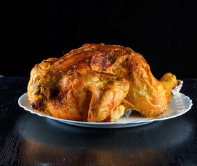 fried chicken whole, on a white plate on a wooden background