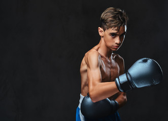 Handsome shirtless young boxer during boxing exercises, focused on process with serious concentrated facial.