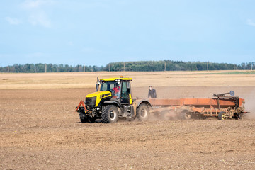 Obraz premium In the autumn, the farmer processes the fields with the tractor and sows the seeds for the next harvest.