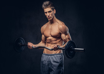 Fototapeta na wymiar Handsome shirtless man with stylish hair and muscular ectomorph doing the exercises with the barbell.