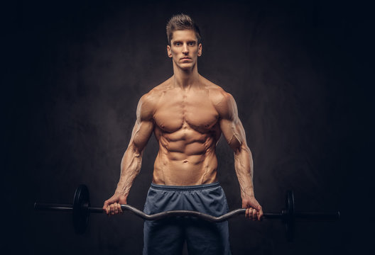 Handsome shirtless man with stylish hair and muscular ectomorph doing the exercises with the barbell.