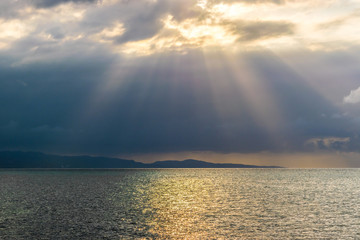 Scenic view of sun rays bursting through clouds over the ocean. Concept of breakthrough, hope,...