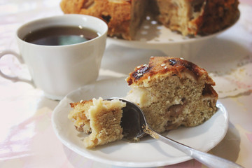 A piece of cake and a spoon on a plate on a background of a cup of tea