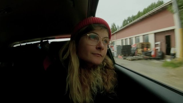 Time lapse of young blonde woman adventurer or traveller in backseat of car during road trip, look out of window at surrounding and views. fast life pace concept and new destinations