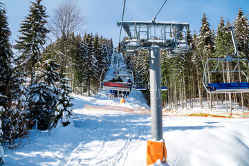 Skiers and snowboarders on a ski lift.view from above on the cable car among the winter forest.