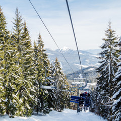 Skiers and snowboarders on a ski lift.view from above on the cable car among the winter forest.