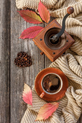  Cup of hot black coffee, coffee mill, coffee beans in the heart shape, warm scarf and autumn leaves. Top view, close-up on  vintage wooden table, autumn concept, background, flat lay