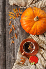 Cup of hot black coffee and pumpkin shaped gingerbread with autumnal leaves, pumpkin and warm scarf. Autumn and Halloween background, top view, close-up on wooden vintage table