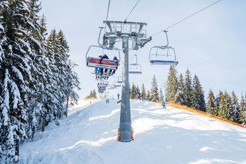 Skiers and snowboarders on a ski lift.view from above on the cable car among the winter forest.