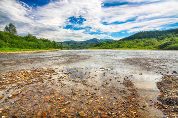Fototapeta premium Mountain river stream of water in the rocks with majestic blue sky