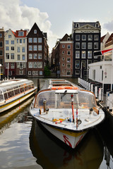 Łódka na amsterdamskim kanale na tle Starówki nad wodą.