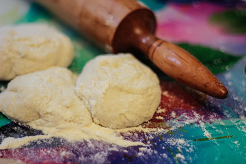 Rolling pin with dough on the table in flour