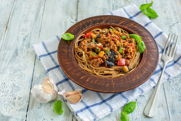 Pasta with bolognese sauce, vegetables and basil.
