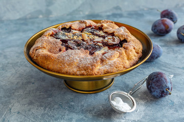Homemade plum pie on a bronze stand.