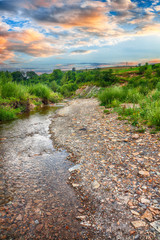 Mountain river stream of water in the rocks with majestic blue sky.