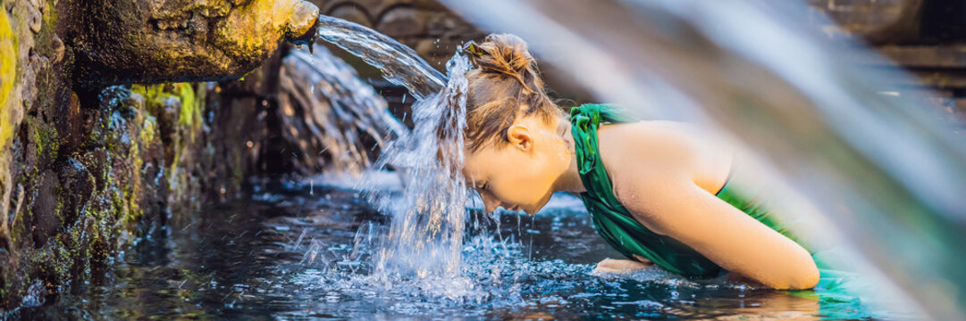 Woman in holy spring water temple in bali. The temple compound consists of a petirtaan or bathing structure, famous for its holy spring water BANNER, long format