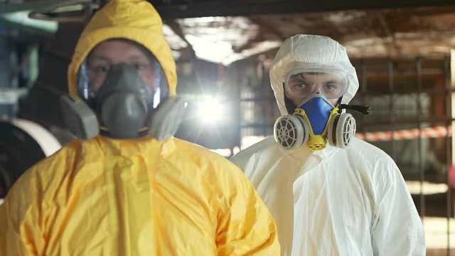 Guys wearing protective uniform looking directly at camera. Two Caucasian men in hazmat suits. Invisible danger. Job. Indoors