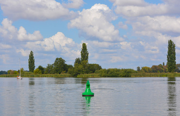Obraz premium Boje und Segelboot auf dem Fluss