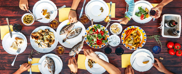 Big family dinner in process. Top view vertical image on table with food and hands