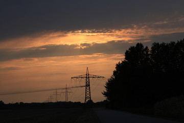 Electricity pylons in the sunset photographed in Germany at the end of a hot summer day
