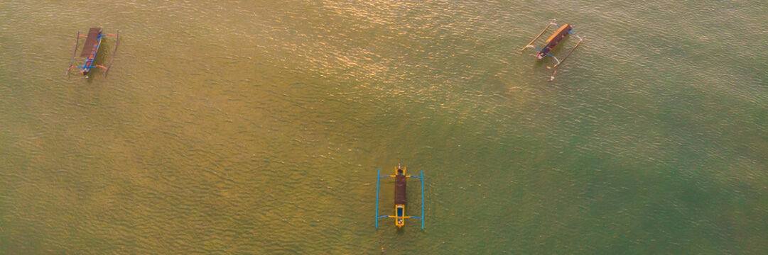 Traditional Balinese boat Jukung at Jimbaran beach at sunset in Bali, Indonesia Photo from the drone BANNER, long format