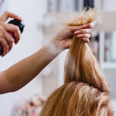 Fototapeta premium Closeup of hairdresser making modern hairstyle using spray