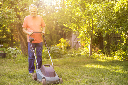 Portrait Of Eldery Senior Man Working In The Summer Garden Walking On A Grass Field