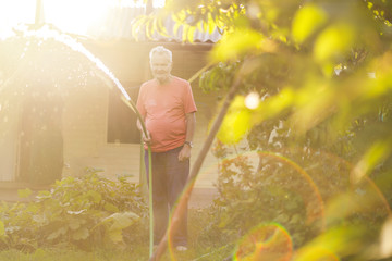 old senior male farmer pouring water on summer day © Mihail