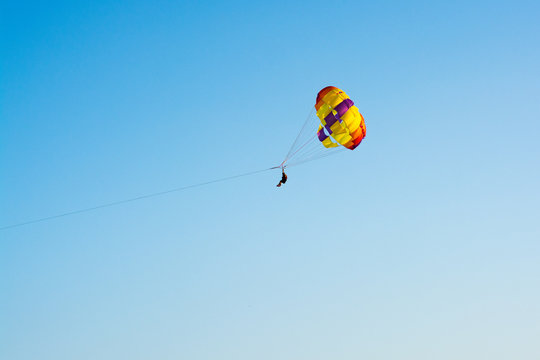 Man flying on a round bright parashute