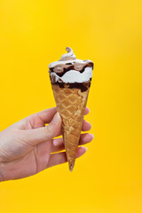 chocolate cream ice cream in waffle cone on yellow background.
