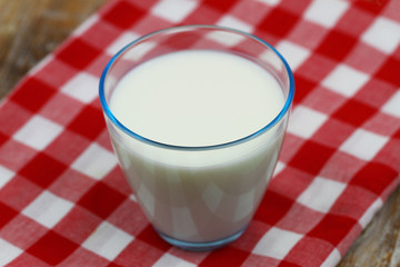 Glass of milk on red and white checkered cloth

