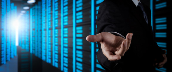 Businessman working with VR wide blank screen computer on server room in background.