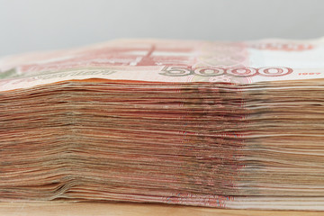 Big stack of Russian money banknotes of five thousand rubles lying on a wooden table