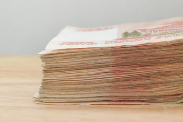 Big stack of Russian money banknotes of five thousand rubles lying on a wooden table